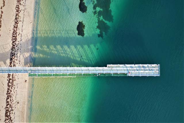 A long dock surrounded by crystal blue water